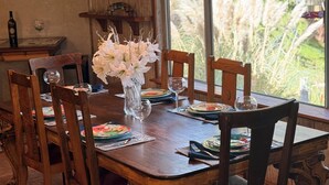Un comedor con mesa de madera, sillas y una lámpara de vidrio emplomado.