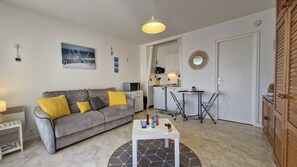 Ein gemütlicher Wohnbereich mit einer Couch, einem kleinen Tisch, einer Küchenzeile und einem Essbereich.
