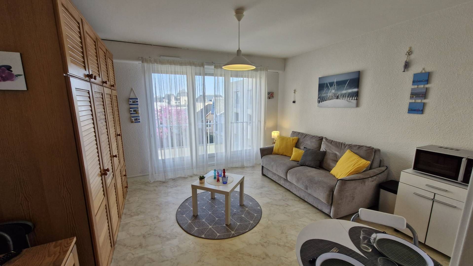 Een woonkamer met een bank, salontafel en een televisie. Er is een schuifdeur naar een balkon.