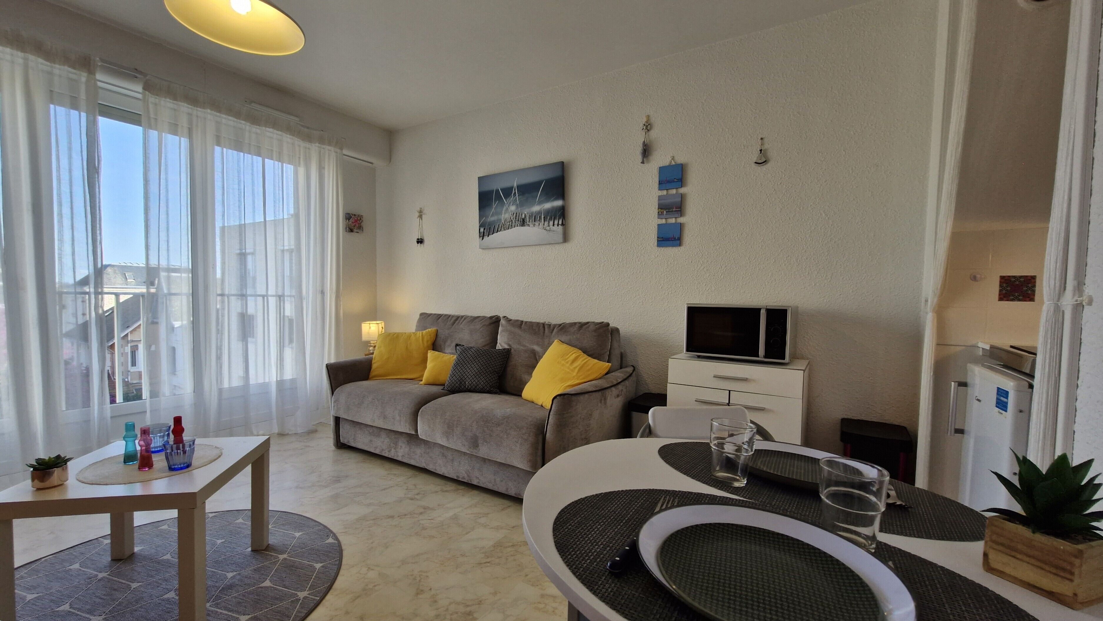 En moderne stue med sofa, spisebord, fjernsyn og køleskab.