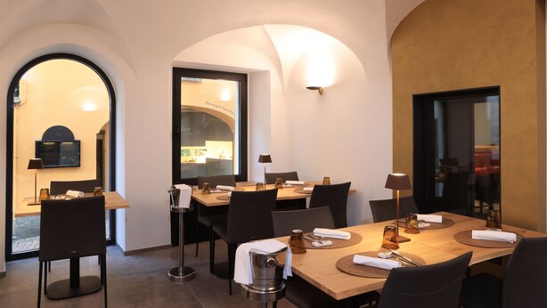 A dining area with a wooden table set for four, black chairs, and a modern chandelier. - Charme Hotel al Torchio  (Ascona)
