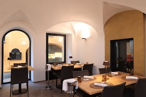 A dining area with a wooden table set for four, black chairs, and a modern chandelier. - Charme Hotel al Torchio  (Ascona)