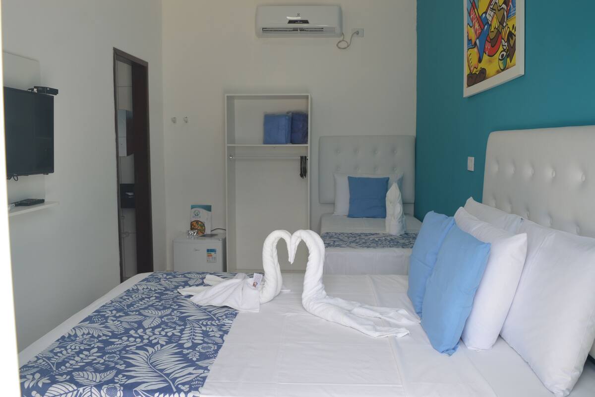 A hotel room with a bed, a wardrobe, a television, and a wall-mounted air conditioner.