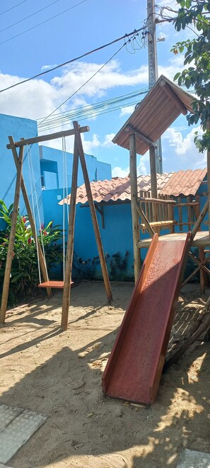 A sandy outdoor area with a wooden swing set and a slide. - Pousada Vovó Zilda (Maragogi)