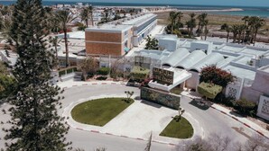 A hotel with a modern design, featuring a central courtyard, a beach view, and a sign indicating the name "Hotel Loasis".