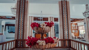 A multi-tiered fountain with red and white flowers, surrounded by wooden columns with patterned designs.