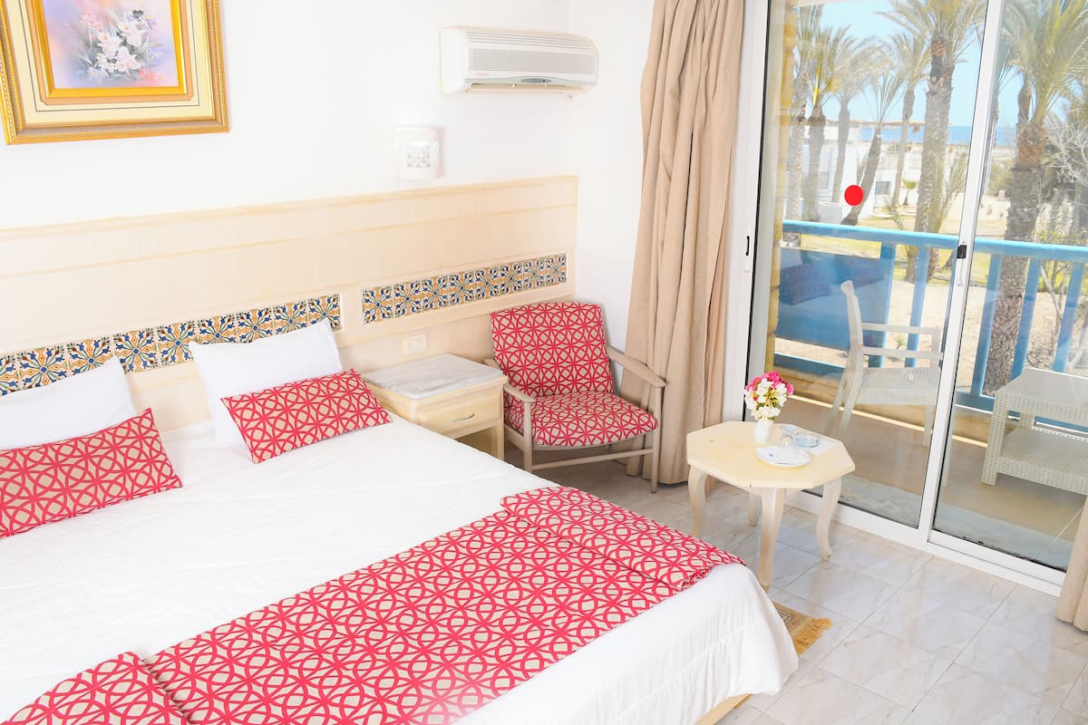 Une chambre d’hôtel avec un lit, une chaise, une petite table et une vue sur l’extérieur.