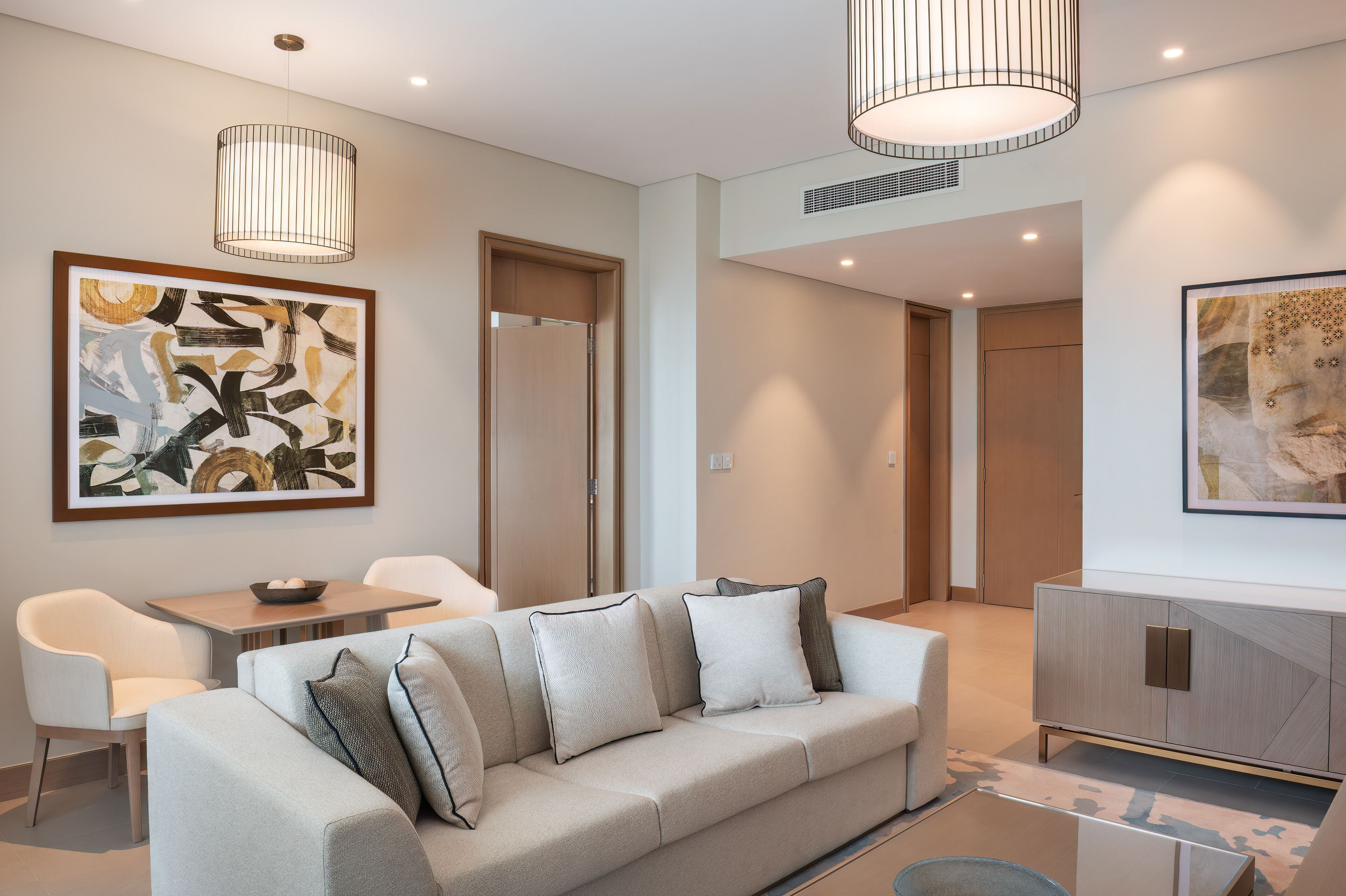 A modern living room with a sofa, chairs, a dining table, and artwork on the walls.