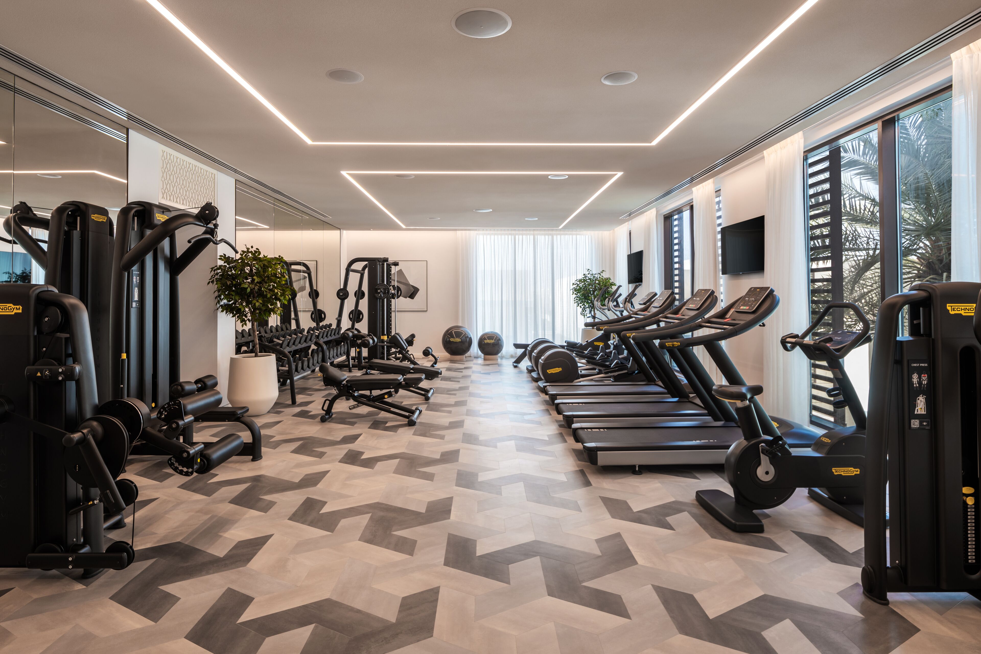 A modern gym with various exercise equipment, including treadmills, weight machines, and free weights.