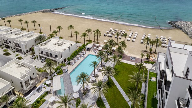 Un complexe hôtelier doté d’une piscine, d’une plage et de palmiers.