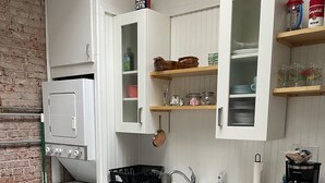 A compact kitchen with white cabinets, a stainless steel sink, and a small refrigerator. - Lower East Side NYC in Old Bisbee (Bisbee)