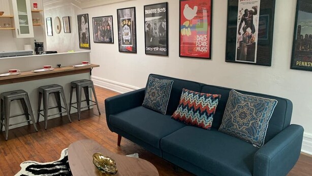 A modern living room with a blue sofa, a wooden coffee table, and a kitchen area with stools. - Lower East Side NYC in Old Bisbee (Bisbee)