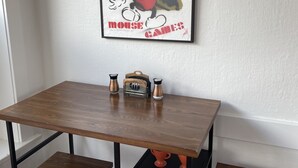 A dining area with a wooden table, two chairs, a coffee maker, and a plate rack. - Lower East Side NYC in Old Bisbee (Bisbee)