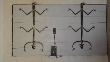 A wall-mounted metal sculpture with four symmetrical arms, each ending in a curved claw-like shape.