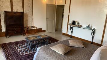 Une chambre à coucher avec un lit, une commode en bois, une petite table avec un livre, un tapis à motifs et une table de chevet avec une lampe.