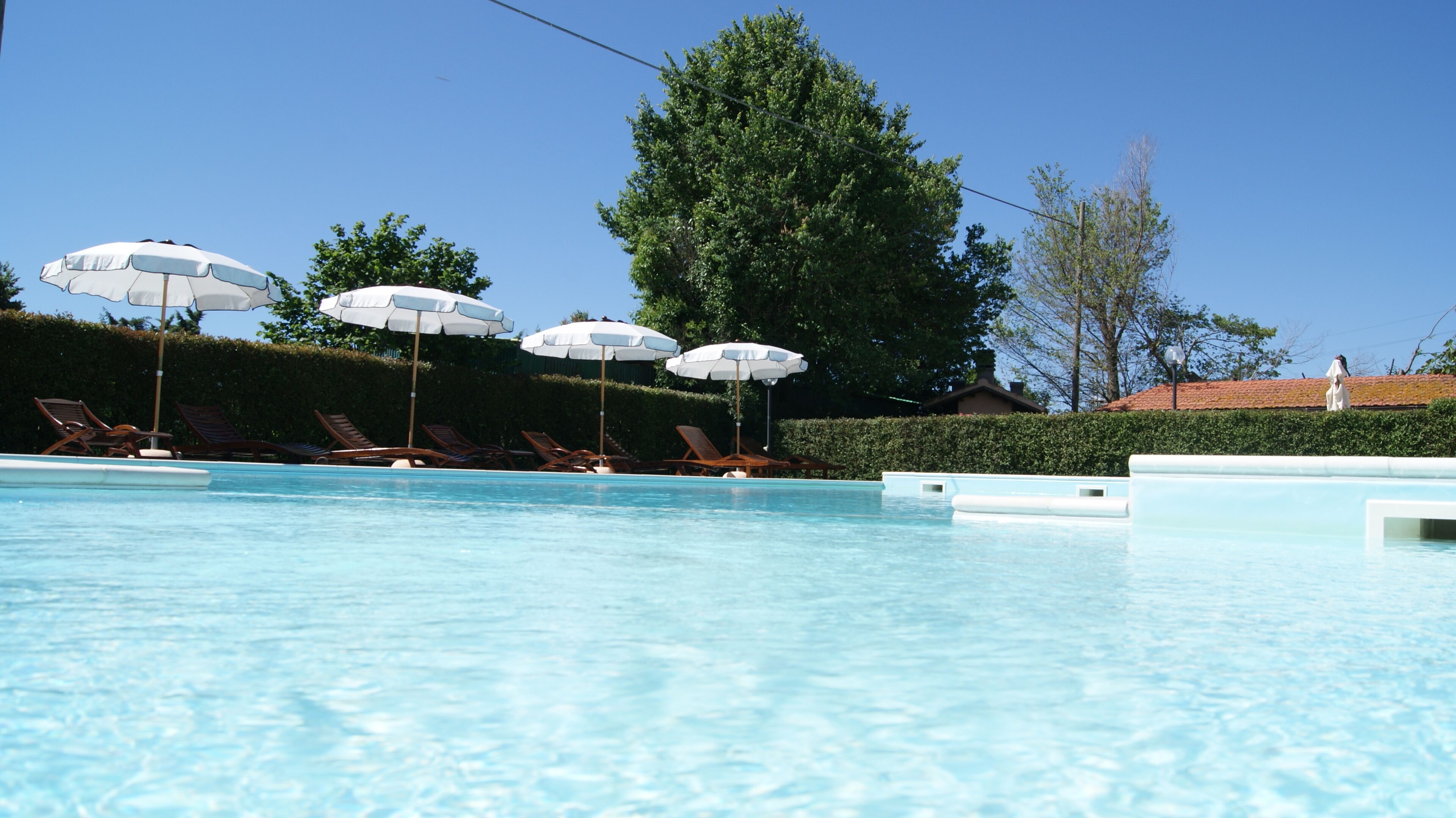 Una piscina con lettini e ombrelloni.