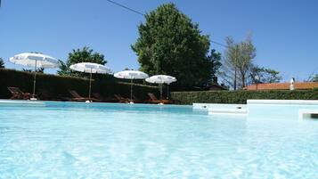 Una piscina con lettini e ombrelloni.