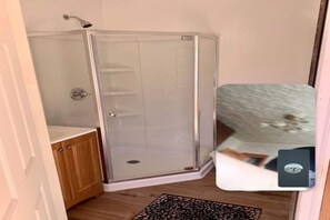 Une douche d’angle avec une porte en verre, un meuble en bois et un tapis à motifs.
