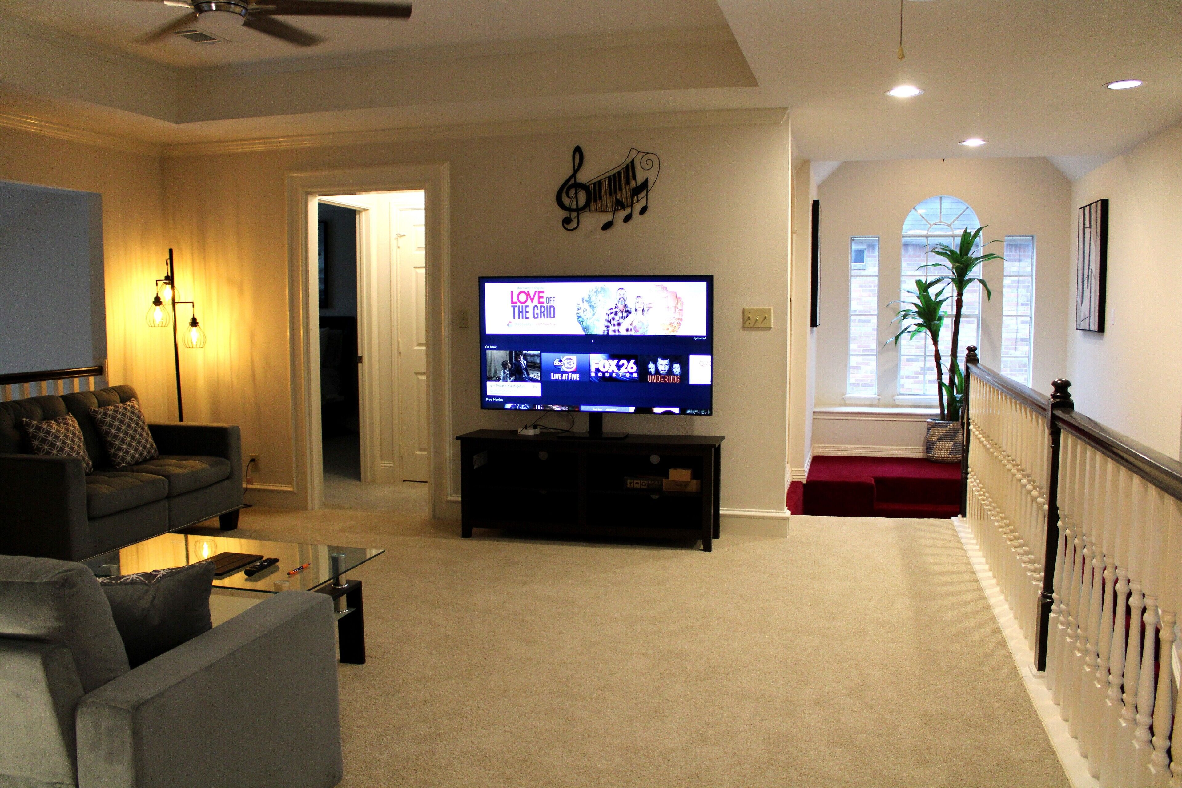A living room with a television, a sofa, a coffee table, and a staircase leading to an upper level.