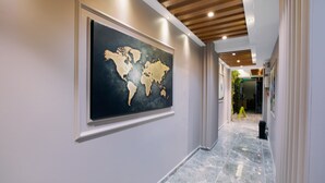 A hallway with a large world map mural, a wooden ceiling, and a marble floor. - Marlen Residence Hotel (Izmir)