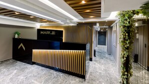 A modern reception desk with a black and gold design, a logo, and a reception area with a marble floor. - Marlen Residence Hotel (Izmir)