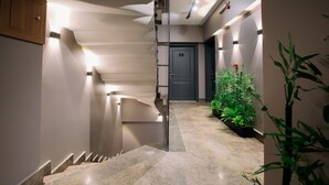 A modern interior with a marble staircase, recessed lighting, and indoor plants. - Marlen Residence Hotel (Izmir)
