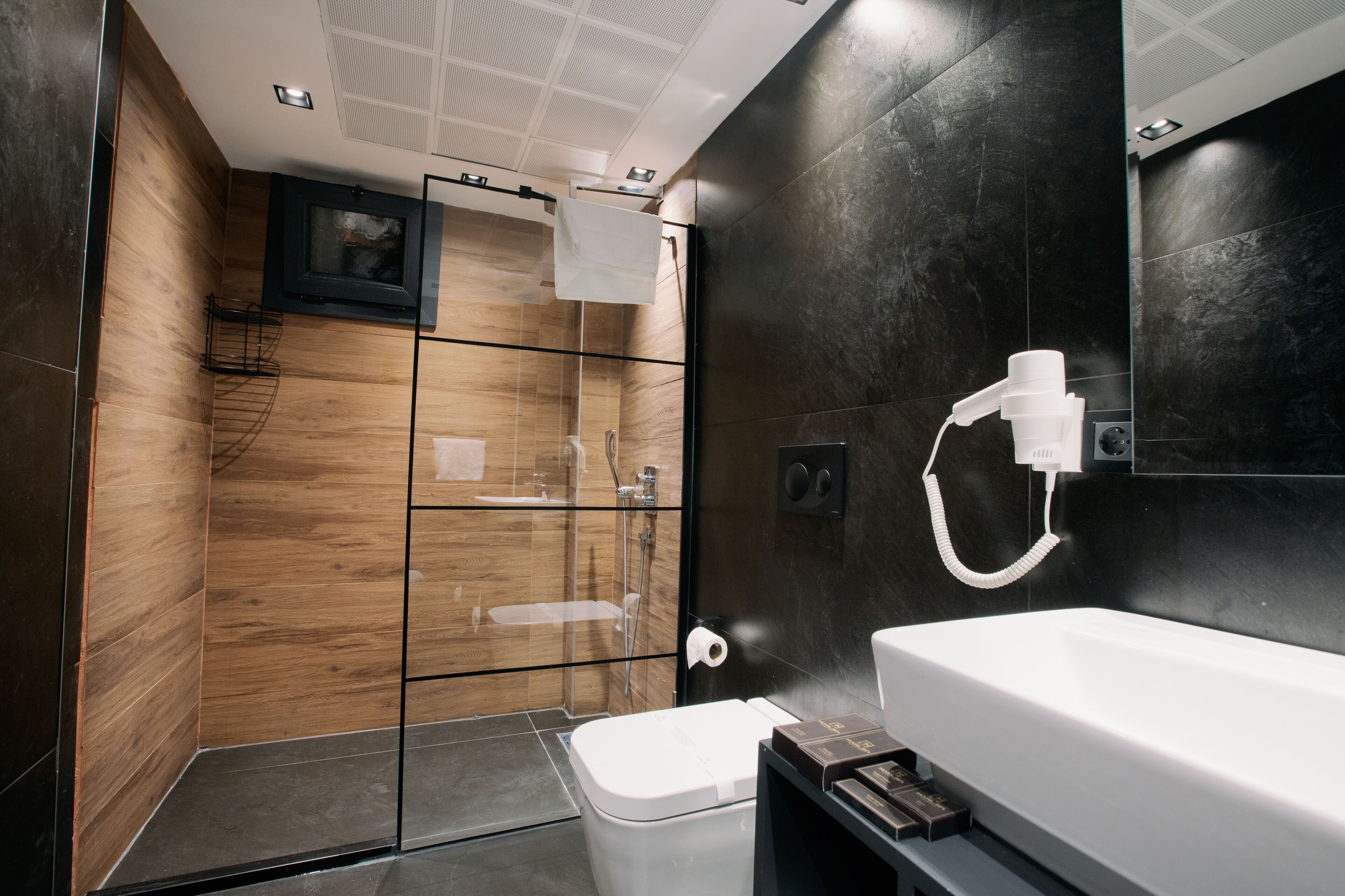 A modern bathroom with a glass-enclosed shower, a white sink, and a large mirror.