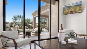 Una sala de estar moderna con un ventanal grande con vistas a un patio, una mesa de centro de madera oscura y un jarrón grande.