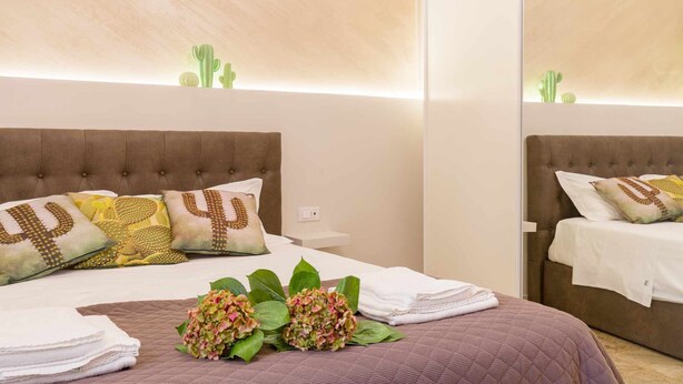 A hotel room with a large bed, multiple pillows, a bedside table, and a mirror. - Casa Al Volto (Verona)
