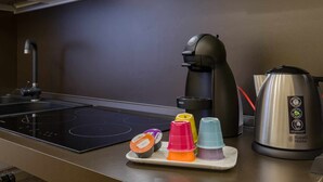 A kitchen with a black induction cooktop, a coffee maker, a kettle, and colorful plastic cups on a tray. - Casa Al Volto (Verona)