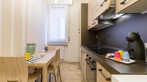 A compact kitchen with a dining table, chairs, a stove, and a coffee maker. - Casa Al Volto (Verona)