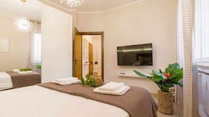 A hotel room with two beds, a TV, a mirror, and a plant. - Casa Al Volto (Verona)