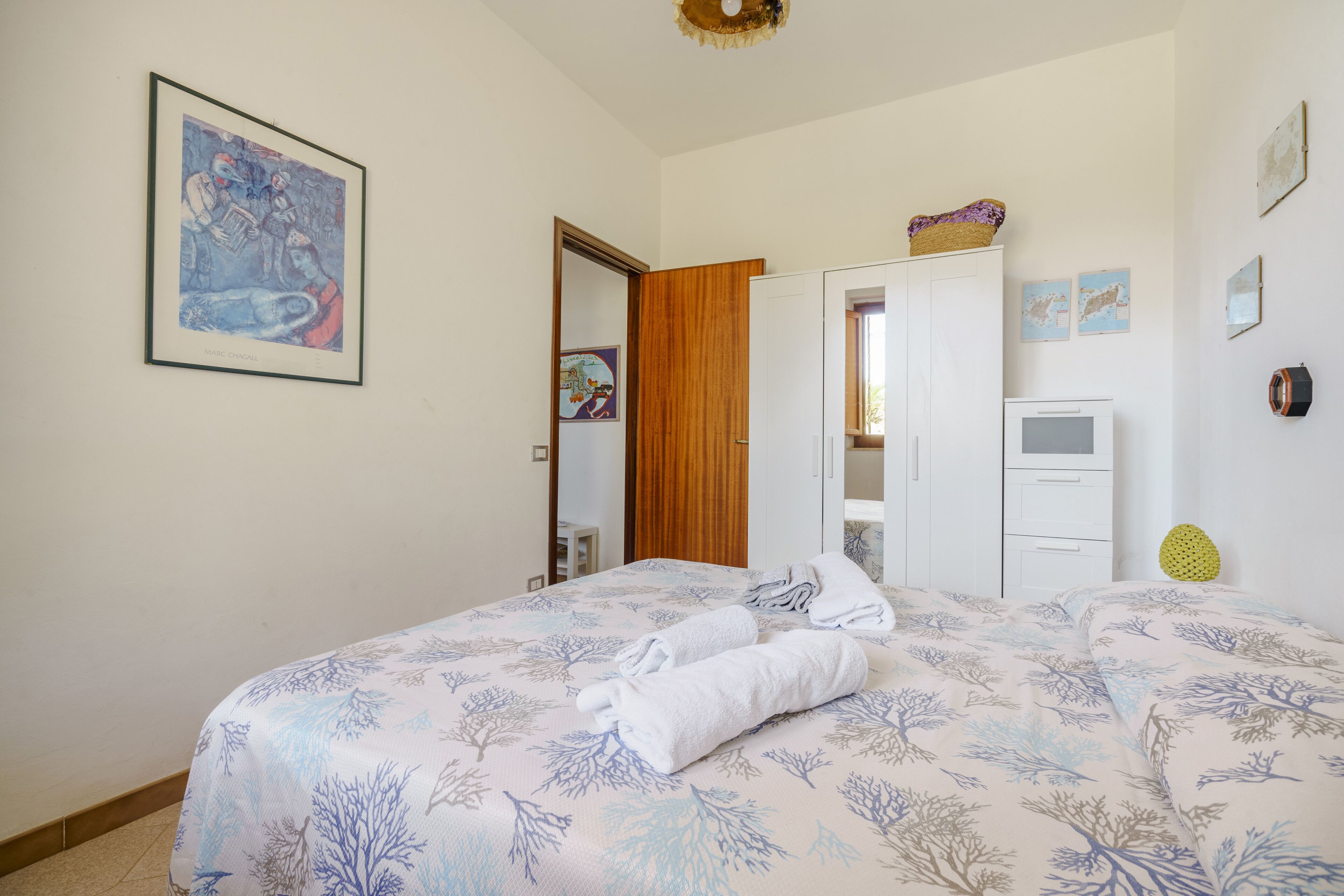 Un dormitorio con cama, armario, escritorio y un cuadro en la pared.