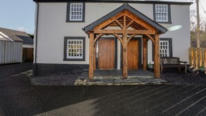 A two-story building with a wooden porch and a black roof. - 2 Ivy House (Corwen)