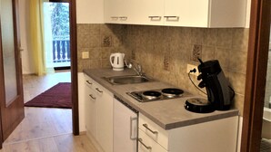 A compact kitchen with white cabinets, a sink, a kettle, and a coffee maker. - Apartment Bergblick in an idyllic location on the edge of the forest, 5 min. to the waterfall (Triberg im Schwarzwald)