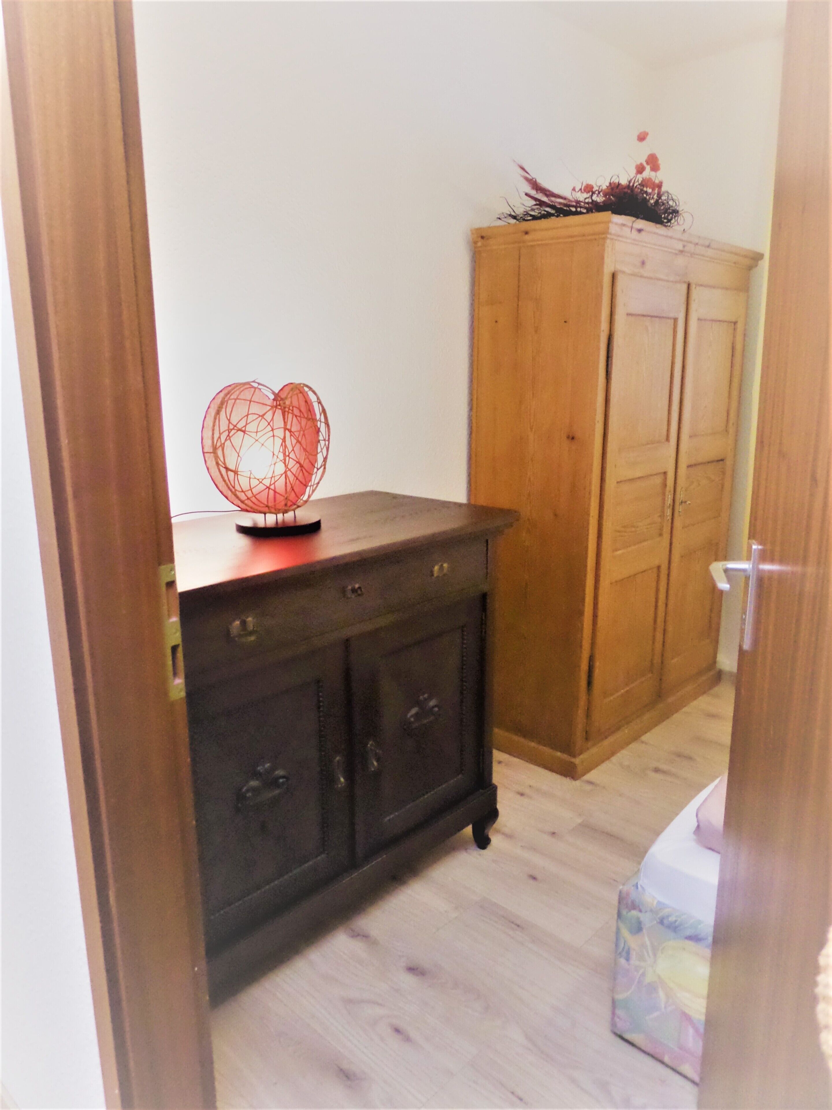 Ein Zimmer mit einem Holzkoffer, einer Zierleuchte und einer Holztür.