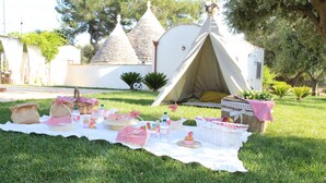 Ein Picknick mit Zelt, Picknickkörben und einem Tisch mit Speisen und Getränken auf einer Wiese.
