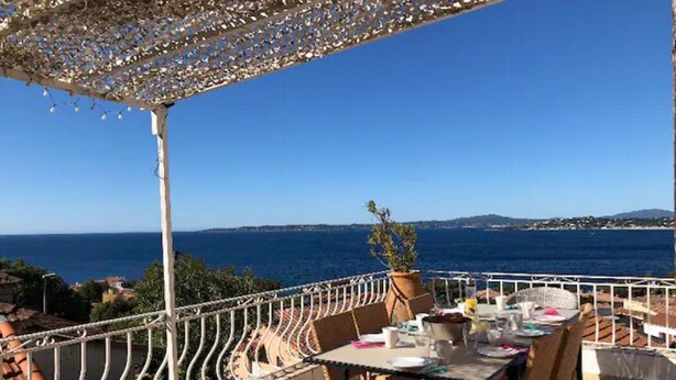 Une terrasse avec une table dressée pour le dîner, offrant une vue sur la côte.