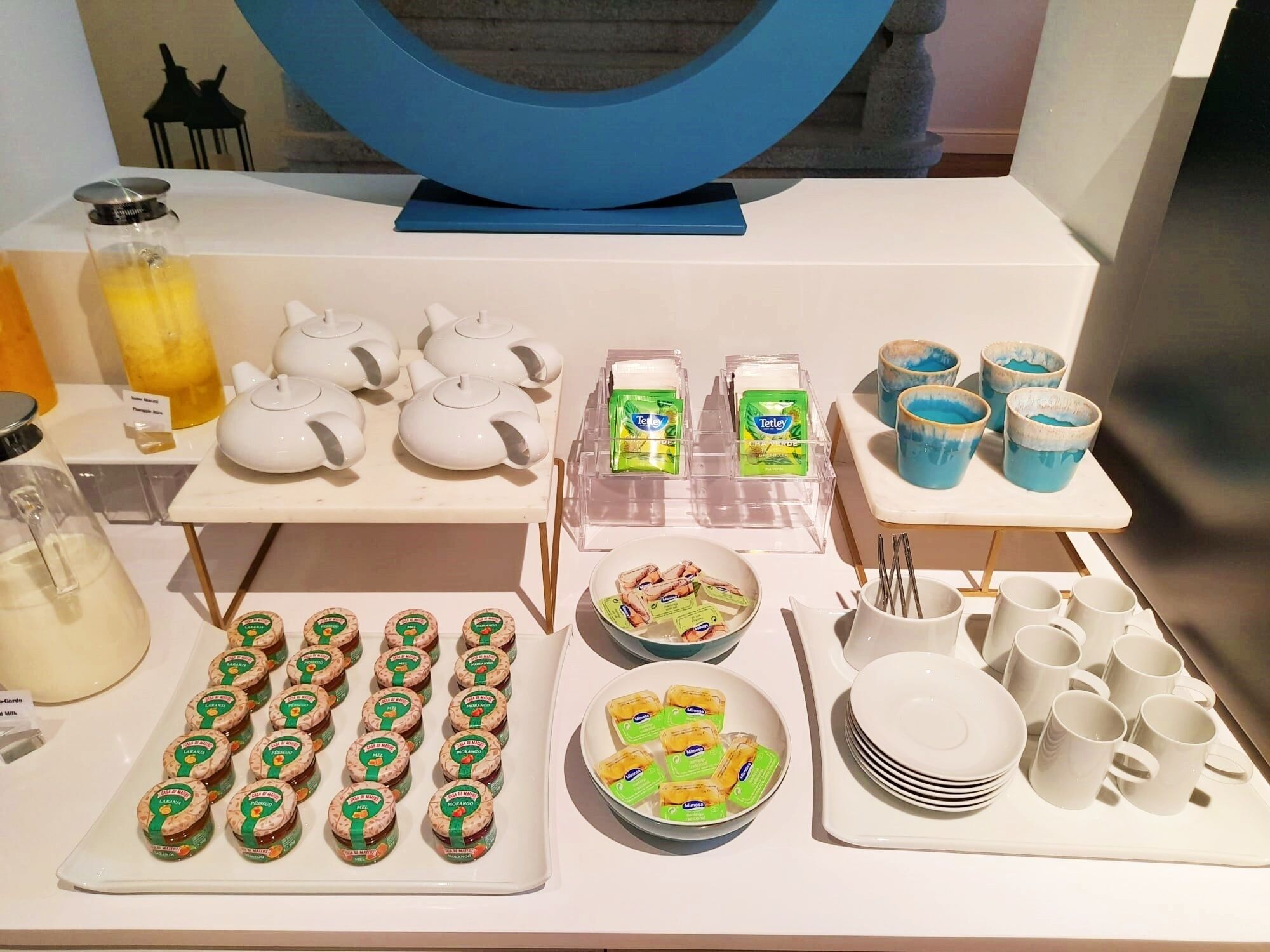 A buffet setup with various food items, including teapots, condiments, and packaged snacks.