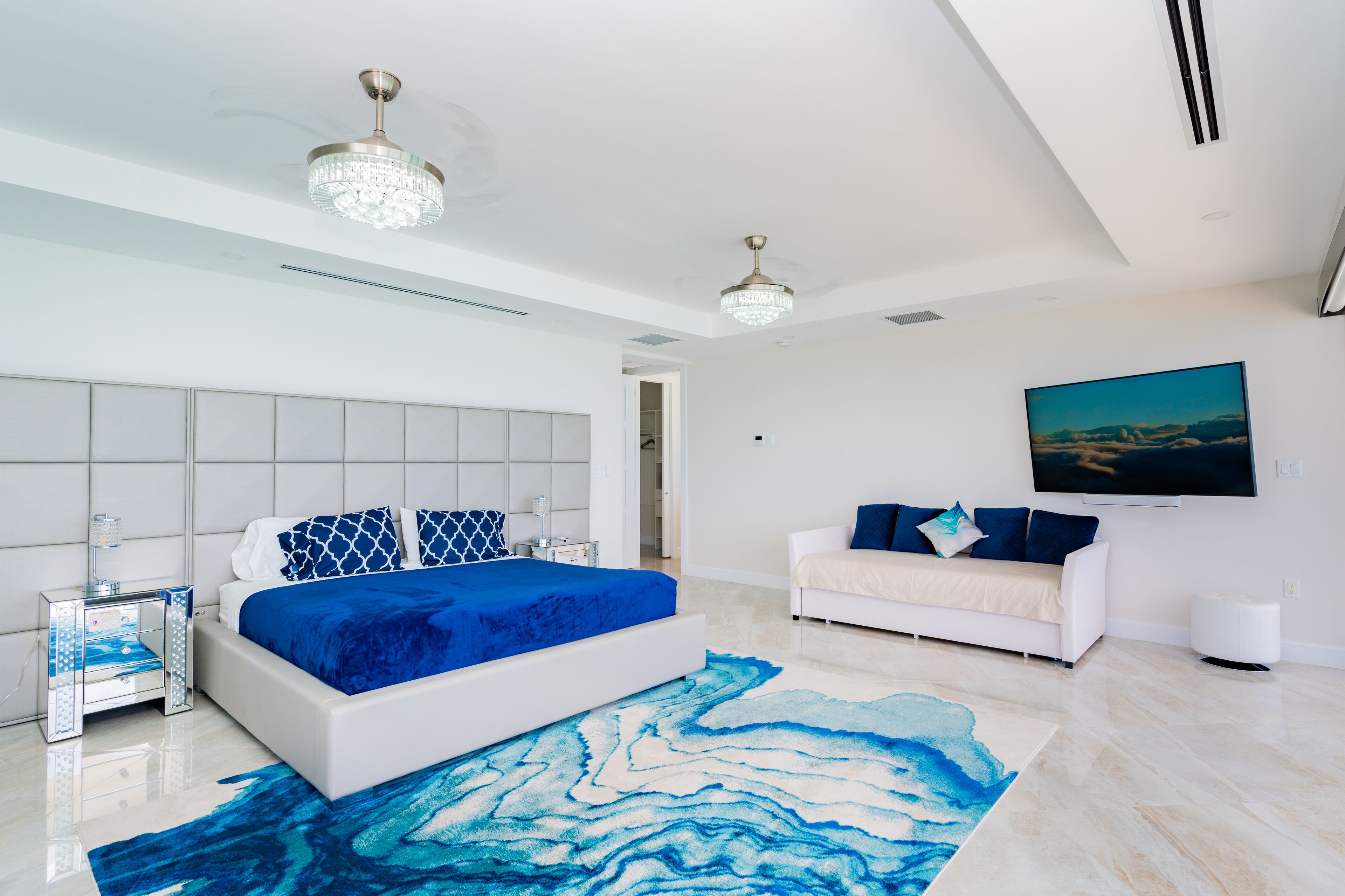 Une chambre à coucher moderne avec un grand lit, un canapé blanc et un tableau accroché au mur.