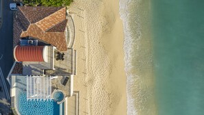 An aerial view of a beachside property with a swimming pool, a covered patio, and a beach. - Oasis 7-stunning private beachfront villa with rooftop pool-by Cayman Villas! (Seven Mile Beach)