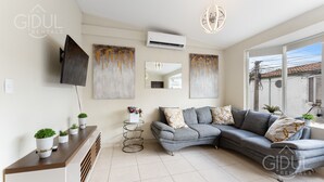 A modern living room with a grey sectional sofa, a mounted TV, and artwork on the walls.