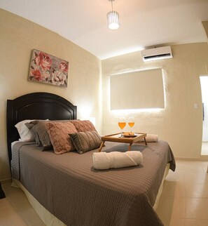 A bedroom with a bed, nightstand, bedside lamp, and a painting on the wall.