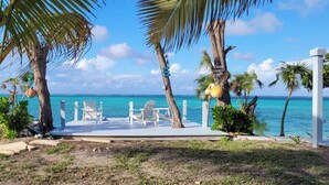 A beachside deck with white chairs and a view of the ocean.