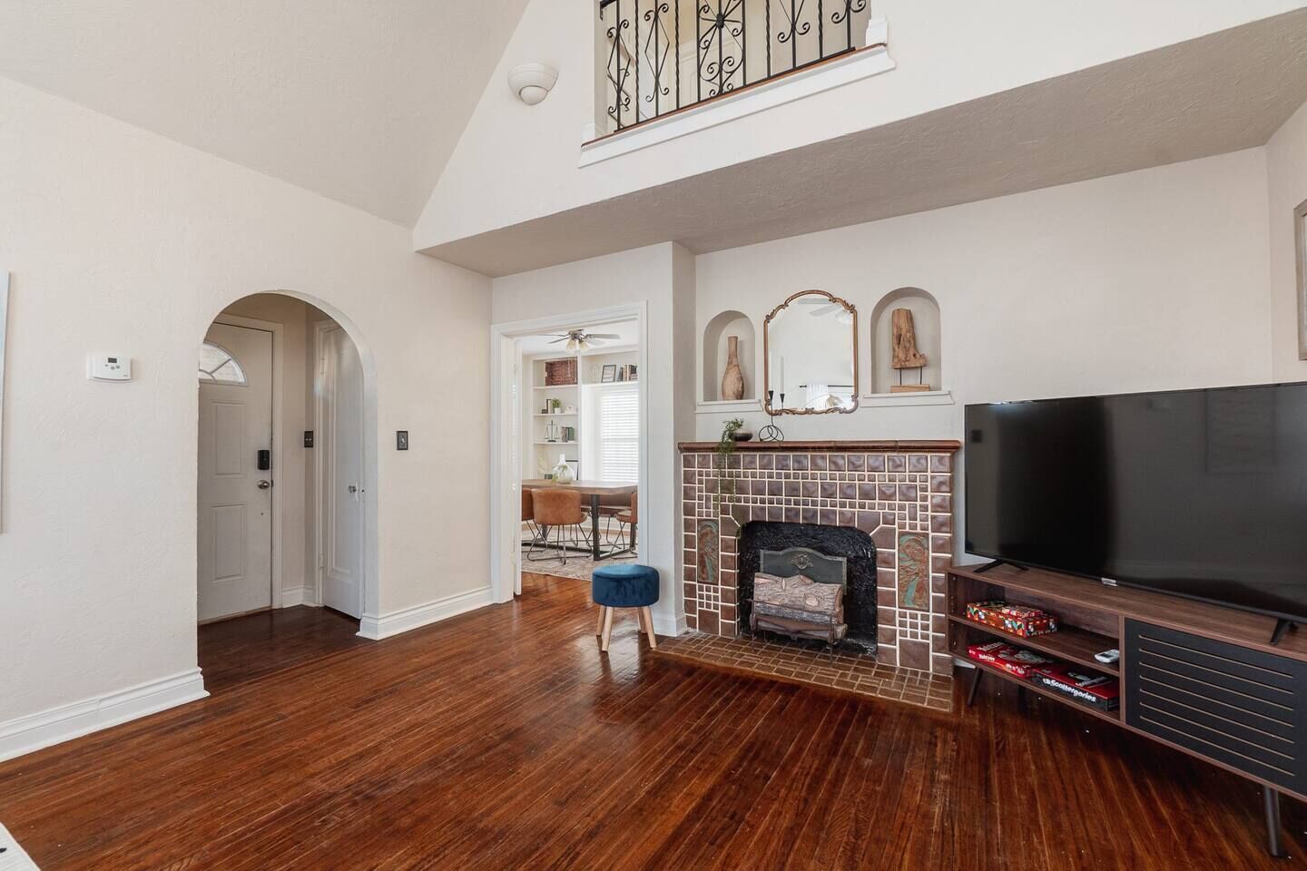 Una sala de estar amplia con pisos de madera, una chimenea, un televisor y una escalera que sube a un nivel superior.