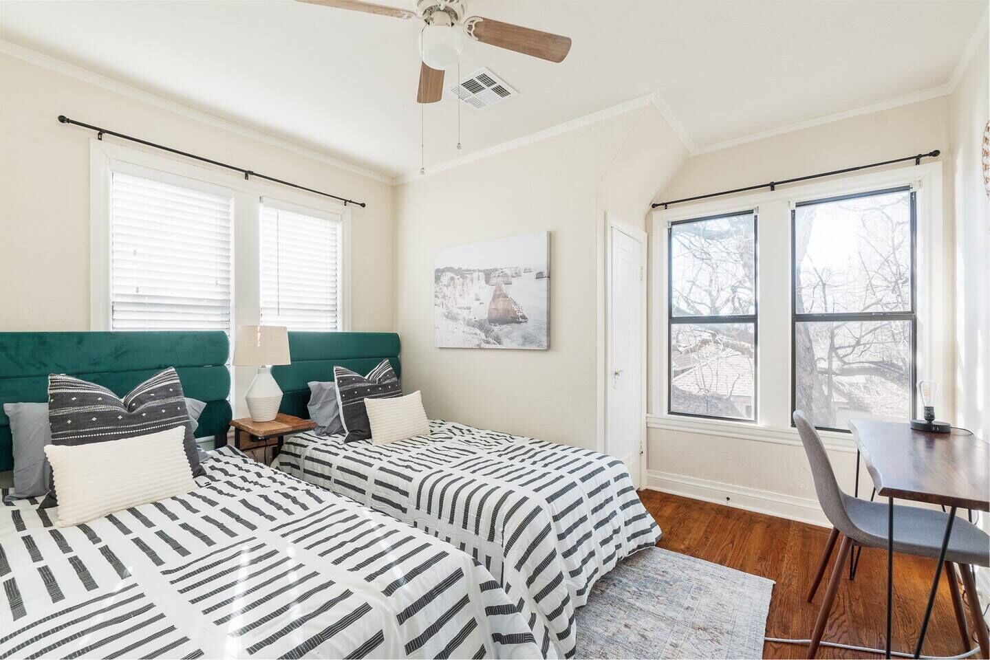 A bedroom with two beds, a desk, and a ceiling fan.