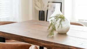 A wooden dining table with a white vase and greenery, surrounded by brown chairs. - The Halcyon- a Cozy 2BR Tudor in Crestwood-Sleeps 6! (Oklahoma City)