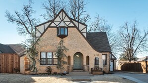A two-story house with a gabled roof, a front entrance with a green door, and a small porch. - The Halcyon- a Cozy 2BR Tudor in Crestwood-Sleeps 6! (Oklahoma City)