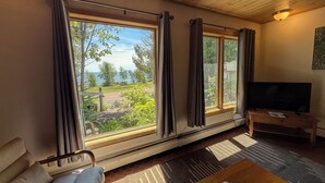 Una habitación con un ventanal amplio, televisión, sofá y suelo de madera.