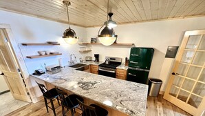 Una cocina moderna con una isla grande, taburetes de bar, estufa y refrigerador.